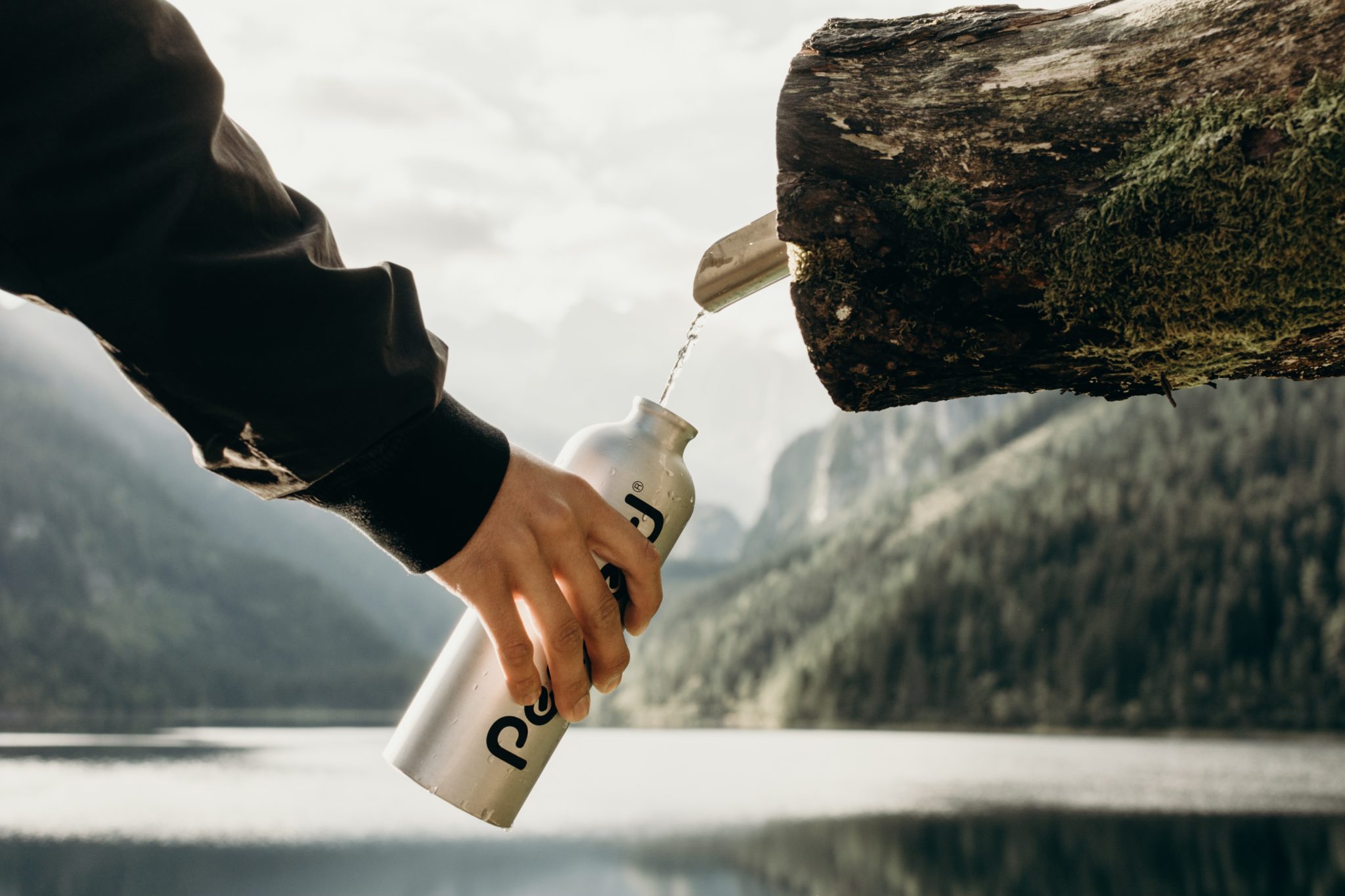 A spout sticking out of a tree pouring filter water into a reusable water bottle.